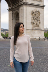 Fototapeta premium Young woman tourist smiling and happy while posing and behind the Triumphal Arch in paris