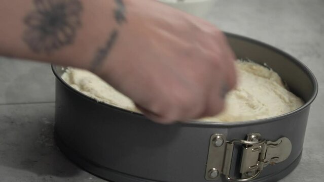 Cheesecake filling spread into springform pan with spoon, right hand