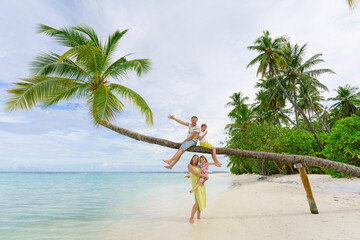 Fototapeta na wymiar Young family on vacation have a lot of fun on palmtree