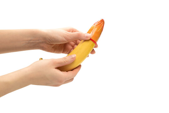 Woman put on a condom on a banana. Isolated on white background.