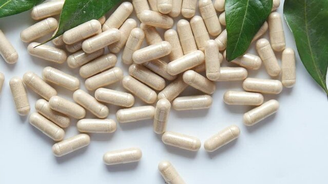 top view of herbal medicine capsule dropping on white 