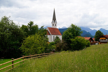 Fototapeta na wymiar a scenic view with lush green alpine meadows and a beautiful old church in the Bavarian village Schwangau in the Bavarian Alps on a hot summer day (Allgaeu, Bavaria, Germany) 