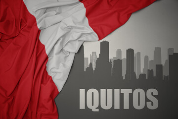 abstract silhouette of the city with text Iquitos near waving colorful national flag of peru on a gray background.