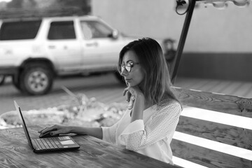 Beautiful businesswoman working with laptop in the summer house in black and white