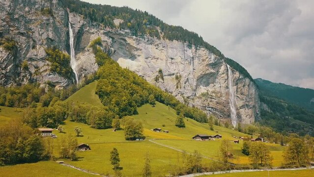 Aerial shot of Lauterbrunnen, Switzerland, showing amazing green valley in between huge mountains and a beautiful waterfall
