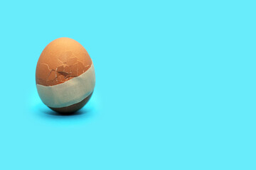 Chicken egg with a crack and a tape stuck on it, the concept of treatment and healthcare. Medical...