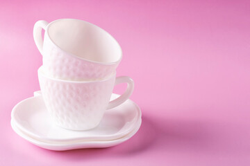 Two beautiful white cups (mugs) in the shape of strawberries and two saucers stacked on top of each other on a pink background. Empty clean dishes. Space for text.