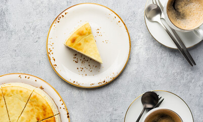 Top view of a piece of cottage cheese casserole with cups of coffee on ceramic plates with cutlery...