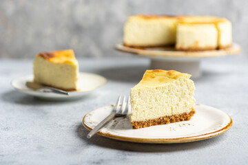 Cottage cheese casserole on shortbread on a white ceramic plate on a concrete light gray background. Portioned sliced cheesecake pie. - obrazy, fototapety, plakaty