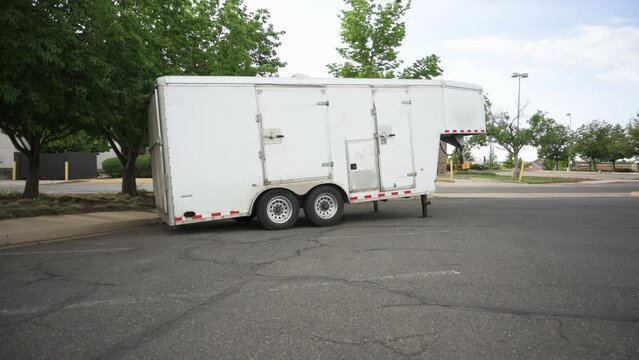 Small white gooseneck cargo trailer in an empty parking lot, static