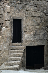 Fototapeta na wymiar Old stone wall with dark wooden gate and door
