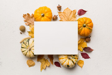 Autumn composition with paper blank and dried leaves with pumpkin on table. Flat lay, top view,...