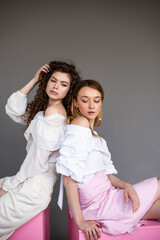 Two fashion female models on a grey background studio portrait of two young stylish girls posing
