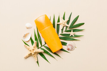 Sunscreen spray bottle. Bottle with sun protection cream and sea shells with tropical green leaf on color background, top view