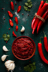 Red hot pepper sauce, top view, on a dark green background, with ingredients, no people,