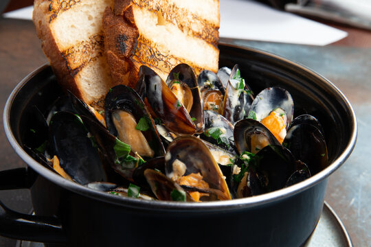 Cooked mussels and fried bread in a pan.