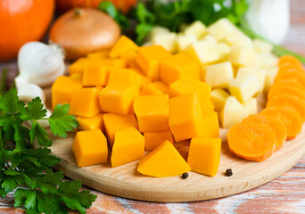 Diced vegetables for cooking pumpkin soup on a wooden background. Healthy food concept. Close-up.