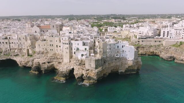 Fast aerial zoom in of city and beach in Polignano a Mare, Italy.