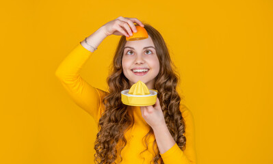 positive teen girl hold orange and juicer on yellow background