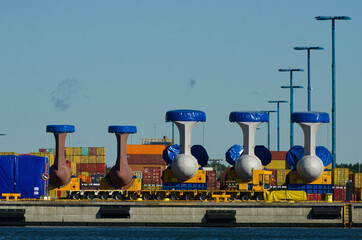 New container ship propellers ready to be installed in a harbor. Big machine parts and containers...