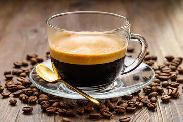 A cup of espresso on a wooden table with beans around. Morning black coffee. Selective focus