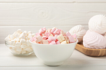 Many different marshmallows in bowls and jars on a white textured wood. White and fruit marshmallow. Sweets and snacks for a snack. Chewing candies close-up. Copy space. Place for text.