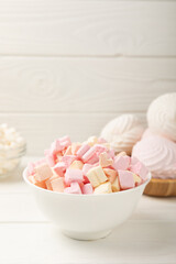 Many different marshmallows in bowls and jars on a white textured wood. White and fruit marshmallow. Sweets and snacks for a snack. Chewing candies close-up. Copy space. Place for text.