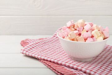 Strawberry marshmallows in a glass bowl on a white textured background with a rustic napkin.Closeup gummies.Snacks and snacks for parties.Spice for coffee and cocoa.Winter food concept.Place for text.