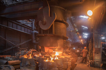 Steel pouring from casting ladle into metal molds.