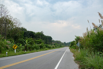Naklejka premium Paved road Thailand.The asphalt road on both sides of the road is covered with grass.