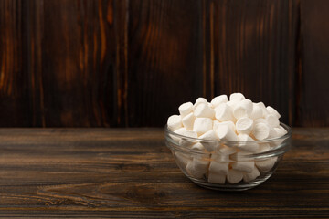 Marshmallow on brown textured wood. White marshmallow. Sweets and snacks for a snack. Chewing candies close-up. Copy space. Place for text.