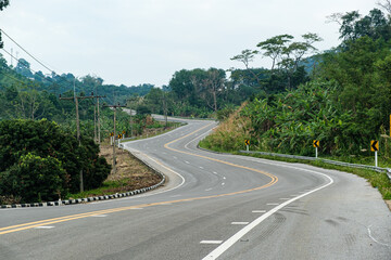 Paved road  Thailand.The asphalt road on both sides of the road is covered with grass.