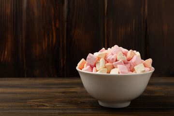 Marshmallow ceramic plate on brown textured wood. Fruit marshmallow.Sweets and snacks for a...
