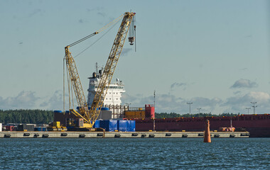 Fototapeta premium Huge industrial harbor cargo crane to load ships with containers and goods