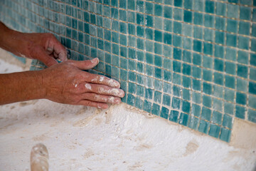 Laying of gresite tiles in the swimming pool, swimming pool repair, man working, green tiles