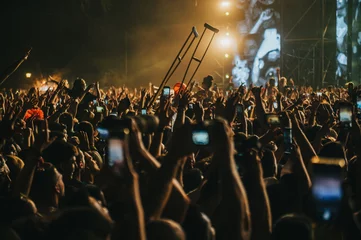 Deurstickers People in a crowd of a music concert using their smartphones and someone holding crutches © Zamrznuti tonovi