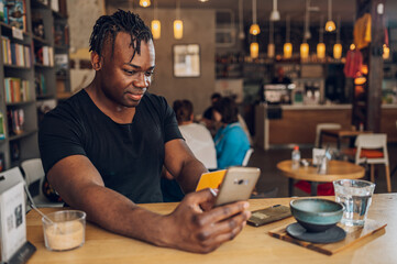 Fototapeta na wymiar African american man using smartphone and credit card in a cafe