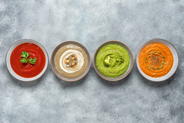 Colored vegetable soup. Assortment of vegan soups. Set of organic soups. Gray concrete grunge background. Top view.