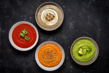 Set of colorful vegetable soups in a bowl. Assortment of vegetarian soups. Black stone background....