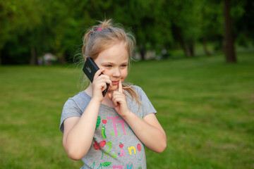 A young girl smiles with her phone in a park in nature