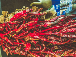 hot, red peppers are dried and hang on the counter. texture with food. pepper with seeds of a small, sharp shape. pepper with green tail