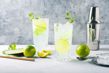 Detox summer cocktail with mint, cucumber and lime or mojito cocktail in highball glasses on a gray concrete stone surface background. Fresh drinks
