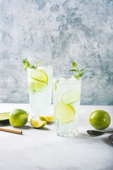 Detox summer cocktail with mint, cucumber and lime or mojito cocktail in highball glasses on a gray concrete stone surface background. Fresh drinks. Copy space