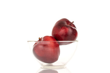 Two ripe red apples in a glass bowl, close-up, isolated on a white background.