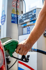 Man pumping gasoline fuel in a car at a self-service gas station. Hand holding a pistol or nozzle...