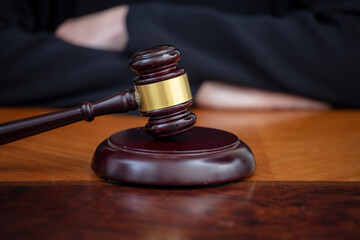 Judge gavel on law court desk, blur female crossed hands, close up view.