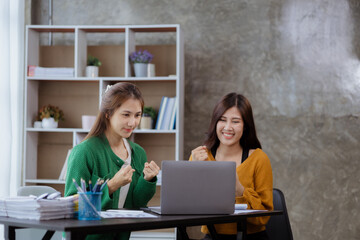 Two women showing joy and looking at data on their laptop, two business women looking at a monthly summary of sales that exceed sales targets and achieve profitable growth. Sales management concept