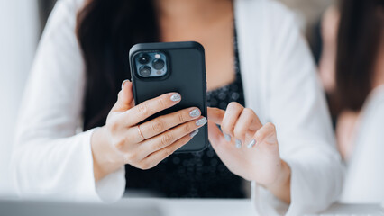 young businesswoman looking at financial information from a mobile phone, she is checking company financial documents, she is a female executive of a startup company. Concept of financial management.