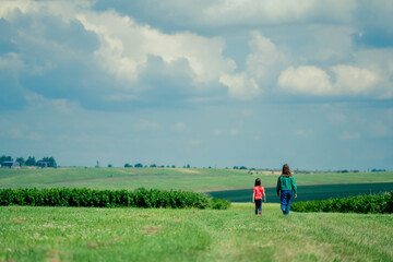 Two beautiful girls walking in the green field. Freedom, nature, happiness and healthy lifestyle concept.