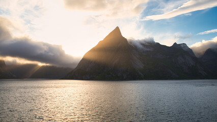 Dramatic sky over the mountains of Lofoten Islands, Norway with rays of sunlight pointing through...